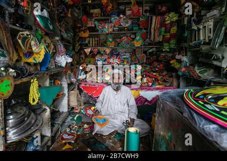 Lahore, Pakistan: Uomo che vende il roba tradizionale di decorazione del camion nel negozio locale Foto Stock