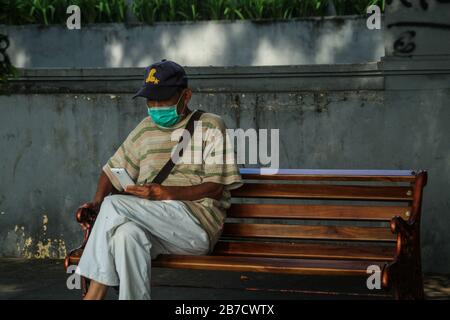 Bandung, Indonesia. 15 Mar 2020. Un uomo indossa una maschera protettiva mentre al telefono come misura preventiva contro la diffusione di Coronavirus vicino alla piazza Alun-alun a Bandung.Il governo della città di Bandung ha cominciato a chiudere tutti gli spazi pubblici per due settimane, Uno dei quali è Piazza Alun-Alun come uno sforzo per prevenire la diffusione di Coronavirus. Credit: Sopa Images Limited/Alamy Live News Foto Stock