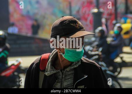 Bandung, Indonesia. 15 Mar 2020. Un uomo guarda mentre indossa una maschera protettiva come misura preventiva contro la diffusione di Coronavirus vicino alla piazza Alun-alun a Bandung.Il governo della città di Bandung ha cominciato a chiudere tutti gli spazi pubblici per due settimane, Uno dei quali è Piazza Alun-Alun come uno sforzo per prevenire la diffusione di Coronavirus. Credit: Sopa Images Limited/Alamy Live News Foto Stock