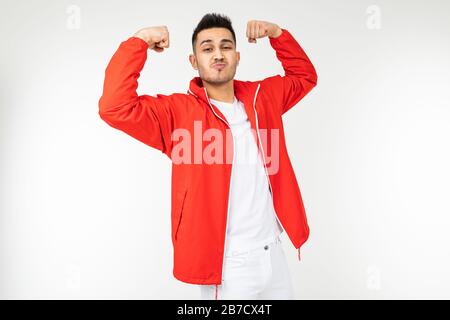 uomo sorridente in rosso sportivo mostra i suoi forti muscoli su uno sfondo bianco con spazio copia Foto Stock