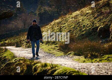 Un fotografo con macchina fotografica che cammina intorno al sentiero del lago di Buttermere Foto Stock