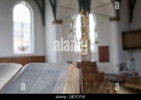 Antica bibbia aperta al capitolo Isaia prohet con la chiesa riformata olandese di Coevorden interno sullo sfondo Foto Stock