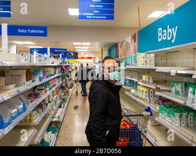 Shpper at Tesco Extra Proteggiti dalle infezioni indossando una maschera facciale. Foto Stock