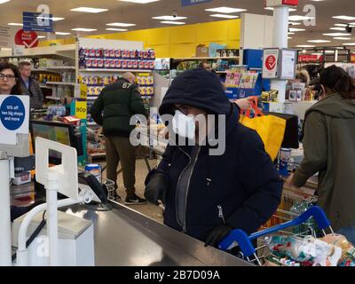 Shpper at Tesco Extra Proteggiti dalle infezioni indossando una maschera facciale. Foto Stock