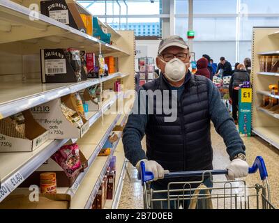 Shpper at Tesco Extra Proteggiti dalle infezioni indossando una maschera facciale. Foto Stock