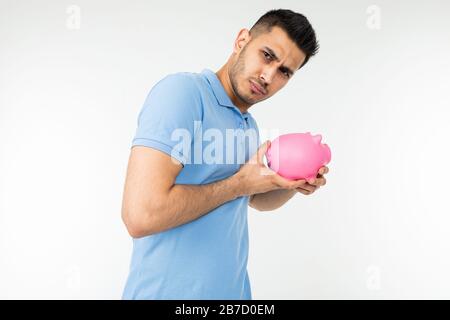 l'uomo sembra sospettosamente tenere una banca piggy nelle sue mani su uno sfondo bianco studio Foto Stock