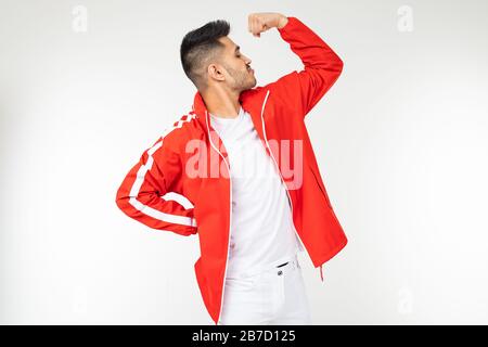 uomo sorridente in rosso sportivo mostra i suoi forti muscoli su uno sfondo bianco con spazio copia Foto Stock