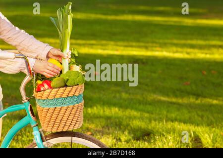 Donna raccolta di verdure fresche dal mercato in cesto in bicicletta Foto Stock