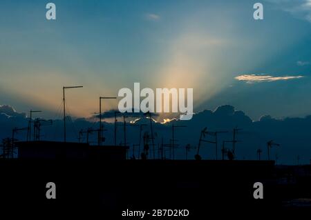 Tramonti dietro le nuvole al tramonto con antenne sui tetti Foto Stock