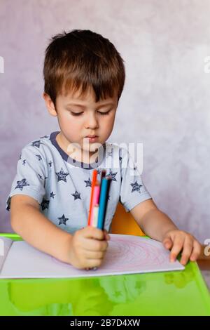 Little Boy Disegno con matite di colore. Little Boy è in possesso di matite di colore. Ci sono molte matite colorate in il ragazzo con le mani in mano. Piccolo Ragazzo trae al Foto Stock