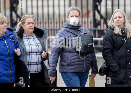 Una donna che indossa una maschera protettiva passa accanto a Buckingham Palace, Londra, come ha affermato il segretario alla sanità Matt Hancock, che i ministri devono ancora decidere se vietare le riunioni di oltre 500 persone nel resto del Regno Unito, Dopo che la Scozia ha detto che avrebbe portato restrizioni a partire da lunedì. Foto Stock