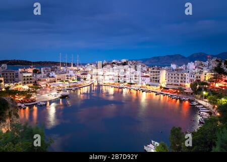 Bellissimo tramonto a Agios Nikolaos città, porto sul mar Egeo. Creta, Grecia. Tranquillo porto del lago Voulismeni. Lungo lungomare con ristoranti. Panor Foto Stock