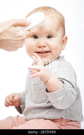 Il pediatra o l'infermiere controlla la temperatura corporea del bambino utilizzando un termometro frontale a infrarossi (termometro a pistola) per verificare l'eventuale presenza di sintomi di malattia Foto Stock