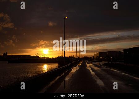 Strada e barche in acqua al tramonto in una giornata nuvolosa Foto Stock