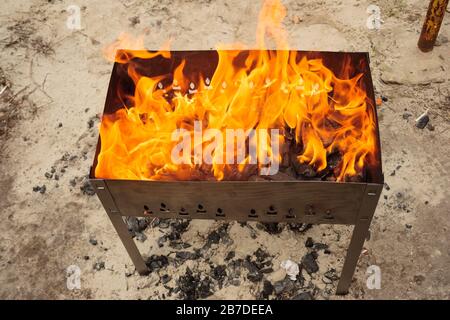 Fiamme calde in un barbecue. Barbecue sulla strada. Barbecue di carne nel cortile nel fine settimana. Foto Stock