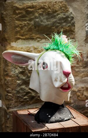 Maschera in lattice di coniglio con fascia di plastica verde erba su uno sfondo di pietra parete, copia spazio per il testo. Vacanza di Pasqua divertente concetto. Gruppo cosl Foto Stock