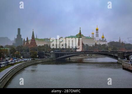 Mosca, Russia - 09 ottobre 2015: Muro rosso del Cremlino e torre con il traffico sul Cremlevskaya Embankment dal fiume Moskva in una tempesta di neve Foto Stock