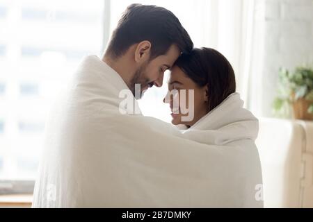 Felice coppia amorevole avvolta in coperta calda che tocca le fronte Foto Stock