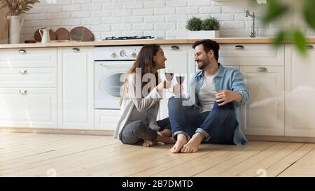 Felice coppia amorevole seduta al piano in cucina, bevendo vino Foto Stock