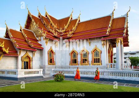 Tempio di marmo buddista conosciuto anche come Wat Benchamabopit Dusitvanaram con monaci che camminano nel giardino, Bangkok, Thailandia. Foto Stock