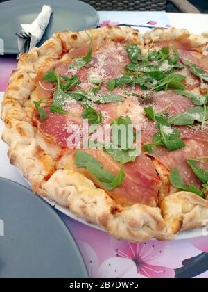 Immagine stock di pizza con prosciutto su un tavolo con due piatti. Foto Stock