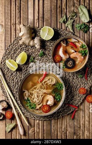 Varietà di zuppe asiatiche. Tradizionale zuppa di zuppa di zuppa di zuppa di zuppa di zuppa di zuppa di tom yum e spiccate con funghi shiitake, gamberi, ingredienti sopra su tovagliolo di paglia Foto Stock