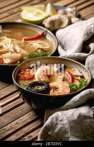 Varietà di zuppe asiatiche. Tradizionale zuppa di zuppa di zuppa di zuppa di zuppa di zuppa di tom yum e pasta con funghi shiitake, gamberi, ingredienti sopra su panno di lino su WO Foto Stock