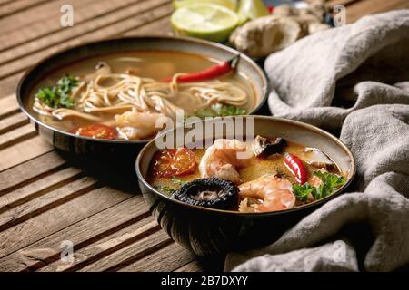 Varietà di zuppe asiatiche. Tradizionale zuppa di zuppa di zuppa di zuppa di zuppa di zuppa di tom yum e pasta con funghi shiitake, gamberi, ingredienti sopra su panno di lino su WO Foto Stock