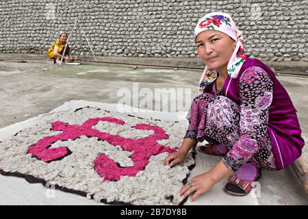 Donna uzbeka in costume locale facendo sentire, a Rishtan, Uzbekistan. Foto Stock