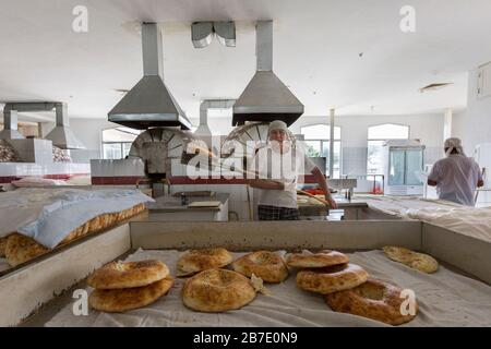 Uomo che cuoce il pane al Bazaar Chorsu, a Tashkent, Uzbekistan. Foto Stock