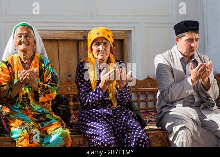 Donne uzbeke e uomo che prega nel cimitero storico di Shahi Zinda, a Samarcanda, Uzbekistan. Foto Stock