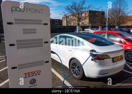 Ricarica di auto elettriche Tesla presso la stazione di ricarica gratuita Pod Point nel supermercato Tesco, Regno Unito Foto Stock