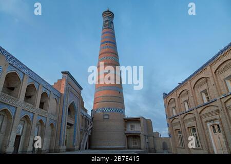 Antica moschea e il suo minareto all'alba, a Khiva, Uzbekistan Foto Stock