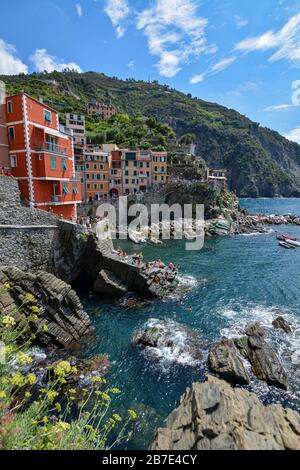 RIOMAGGIORE, ITALIA - 15 agosto 2019: Vista su Riomaggiore e sul mare e le scogliere delle cinque Terre in una giornata di sole Foto Stock