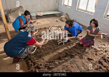 Gente del posto che fa il tappeto di feltro in modo tradizionale, in Issyk Kul, Kirghizistan Foto Stock