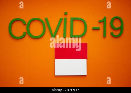 Bandiera dell'Indonesia e Word COVID-19 in cartoncino verde, isolato su sfondo arancione. Organizzazione Mondiale della Sanità CHE ha introdotto nuovo Foto Stock