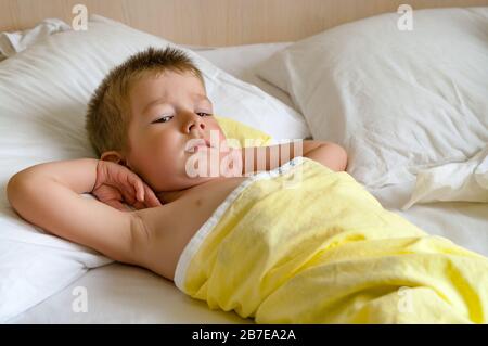 Carino bambino sdraiato a letto prima di dormire. Foto Stock