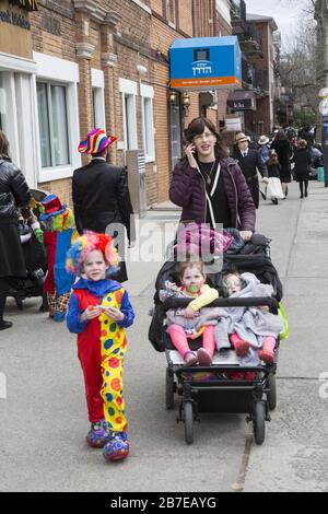 La comunità ebraica ortodossa di Borough Park Brooklyn celebra la festa di Purim indossando costumi, donando ai poveri, mangiando cibi gustosi e, in genere, regalando un buon tempo. Persone sulla 13th Avenue. Purim viene celebrato ogni anno il 14° mese ebraico di Adar . Commemora la salvezza del popolo ebraico nell'antico impero persiano dalla trama di Haman "per distruggere, uccidere e annientare tutti gli ebrei, giovani e anziani, bambini e donne, in un solo giorno", come riportato nel Megillah (libro di Esther). Foto Stock