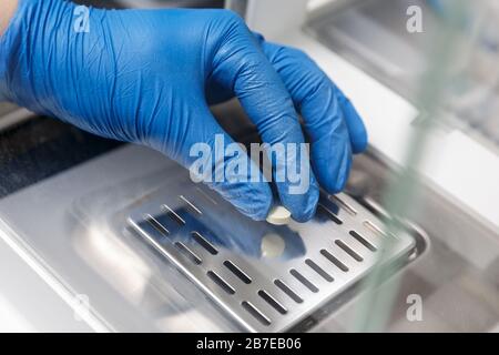 Farmacista in guanti per uso medico che pesano una nuova pillola in un laboratorio farmaceutico. Concetto di industria farmaceutica Foto Stock