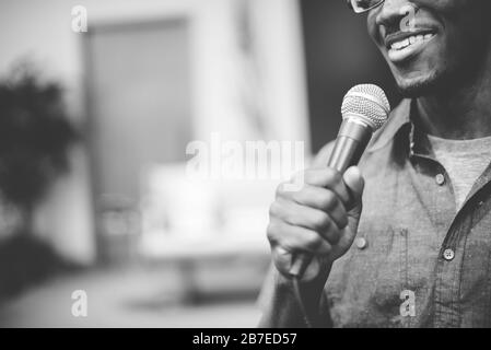 Immagine in scala di grigi di un felice uomo afroamericano che parla sul microfono alla chiesa Foto Stock