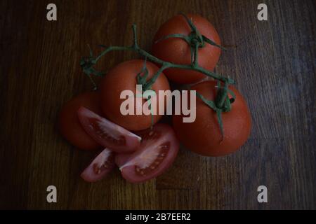 i pomodori tagliati e buchi con gambo su tagliere di legno Foto Stock