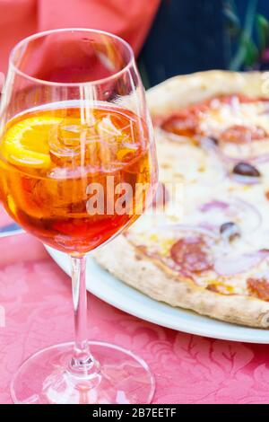 Un bicchiere con un luminoso liquido arancione, ghiaccio e una fetta di arancia, Spritz Aperol cocktail Foto Stock