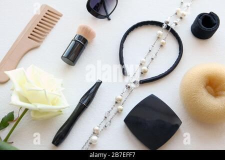 Spazzola in legno, occhiali da sole, barretta e croccante isolato su bianco. Attrezzi per parrucchieri piatti neri e altri accessori di bellezza per donna con bianco Foto Stock