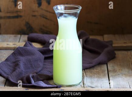 Siero di latte freddo in una bottiglia di vetro su uno sfondo di legno. Foto Stock