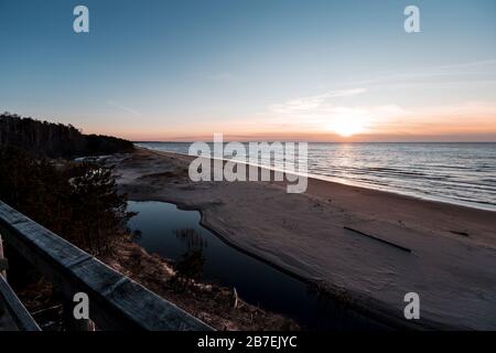 Tramonto a Saulkrasti duna bianca. Vista dal sentiero in legno sul mare, sul piccolo fiume e sul cielo Foto Stock