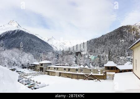 Vista panoramica del villaggio invernale di Dombay. In primo piano c'è il centro commerciale incompiuto. Picchi di montagna contro il cielo nuvoloso. Fiaba di neve Foto Stock