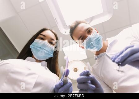 L'uomo guarda con gioia verso il basso. Ispezione presso il dentista dal punto di vista del paziente. Foto Stock