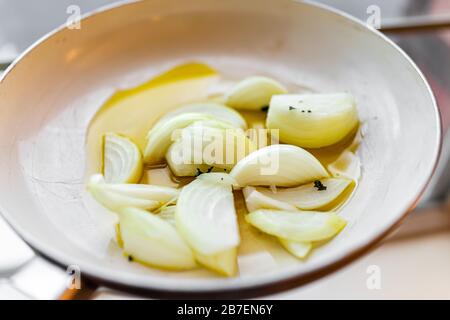 Padella con cipolle tritate scalogno verdure macro primo piano cottura in olio d'oliva in cucina che mostra la consistenza Foto Stock