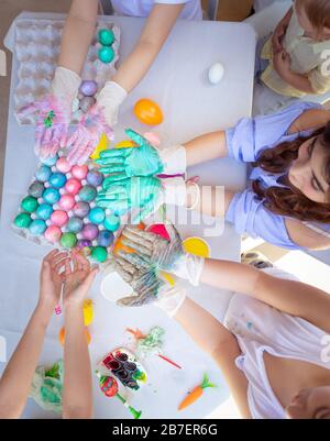 Festa di Pasqua, scolaresche che dipingono le uova, il cibo tradizionale di Pasqua, le mani dei bambini sono macchiate con vernice multicolore, arredamento festoso fatto a mano Foto Stock