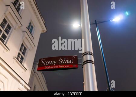 Nowy Swiat (nuovo mondo) segno di strada nel centro storico da Krakowskie Przedmiescie strada di notte con lampada posta a Varsavia, Polonia Foto Stock